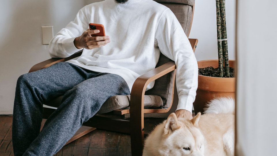 Hombre sentado usando el móvil con su perro al lado